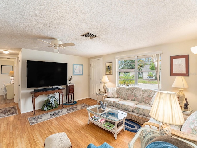 living room featuring hardwood / wood-style floors, a textured ceiling, and ceiling fan