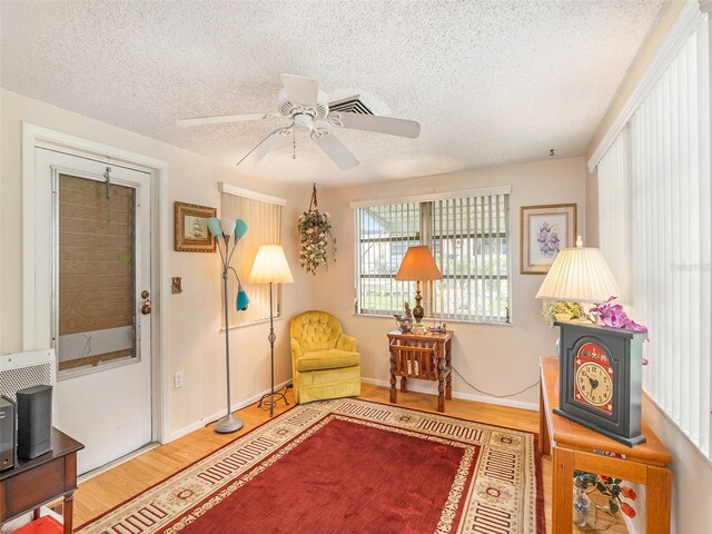 living area with hardwood / wood-style floors, a textured ceiling, and ceiling fan