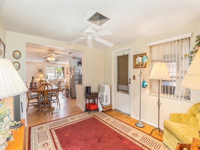 living room featuring ceiling fan, wood-type flooring, and a textured ceiling