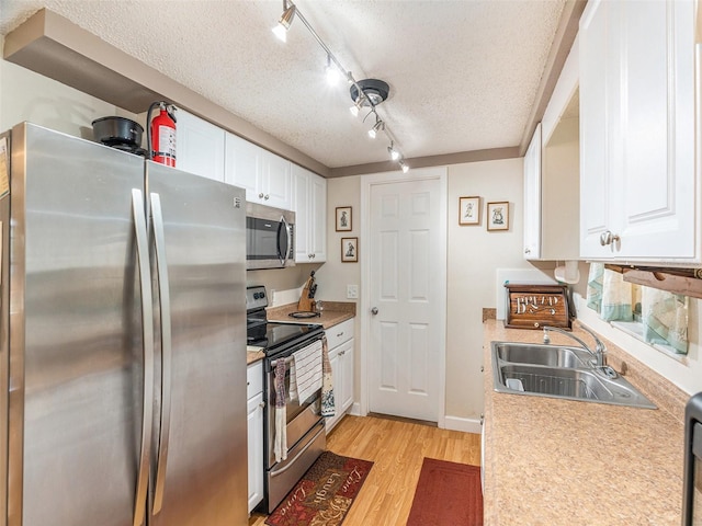 kitchen with white cabinetry, stainless steel appliances, a textured ceiling, and sink