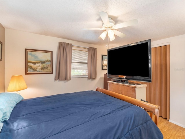 bedroom featuring a closet, a textured ceiling, light wood-type flooring, and ceiling fan