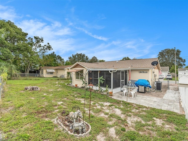 back of property featuring a yard, a sunroom, central AC, and a patio