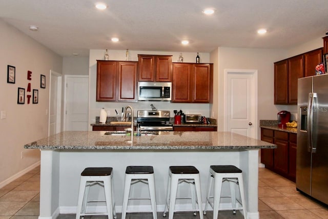 kitchen featuring appliances with stainless steel finishes, a center island with sink, and a breakfast bar area