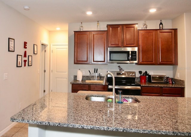 kitchen with light stone counters, sink, light tile patterned floors, and appliances with stainless steel finishes