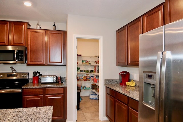 kitchen featuring appliances with stainless steel finishes, light stone counters, and light tile patterned flooring