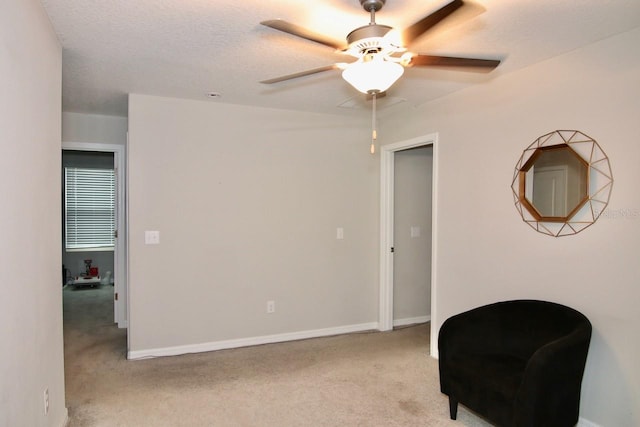 living area with a textured ceiling, ceiling fan, and light carpet