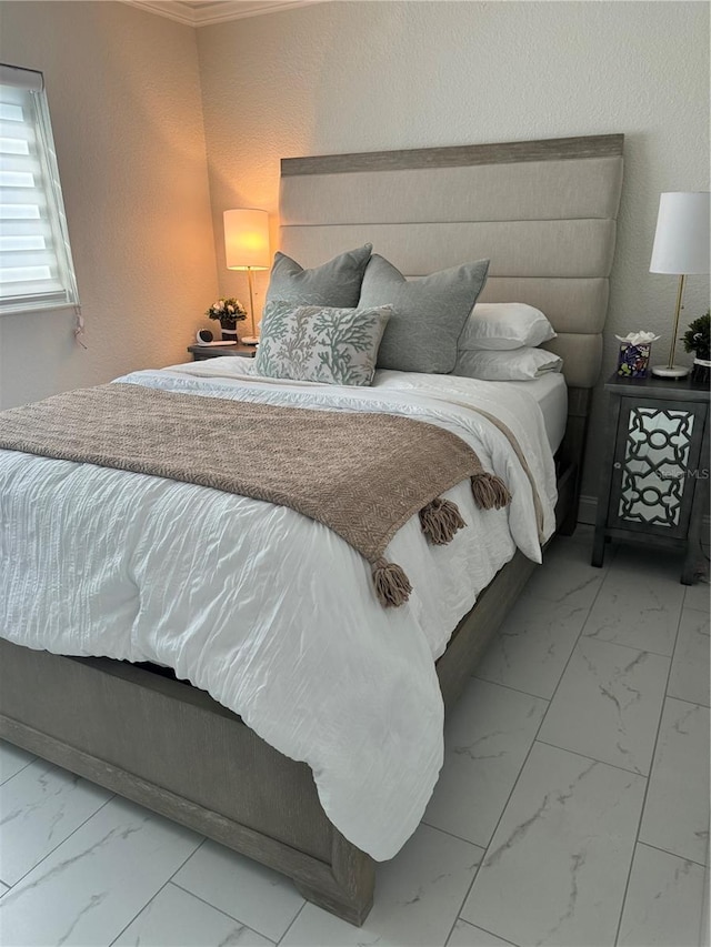 bedroom with a textured wall, marble finish floor, and ornamental molding