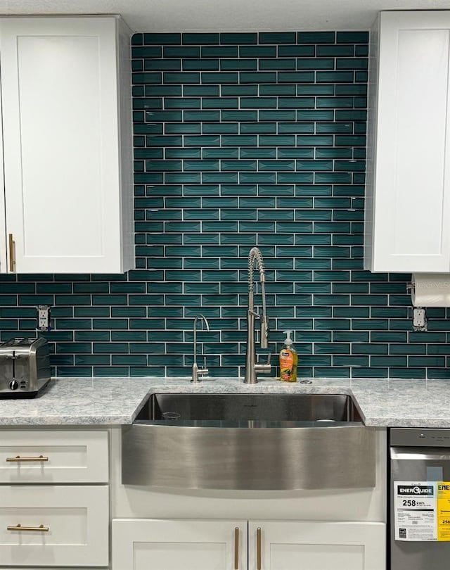 kitchen featuring white cabinets, a toaster, decorative backsplash, and a sink