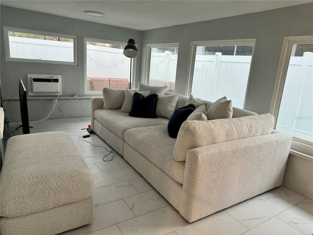 living room featuring marble finish floor, a healthy amount of sunlight, and a wall unit AC