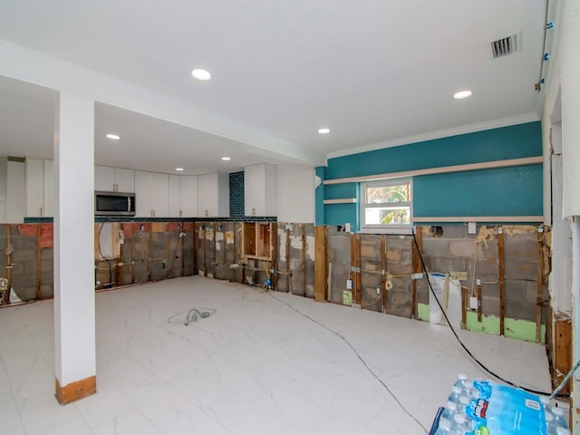 below grade area with ornamental molding, visible vents, and recessed lighting