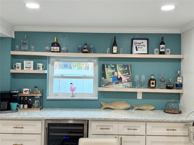 bar featuring beverage cooler, a textured wall, a dry bar, ornamental molding, and recessed lighting