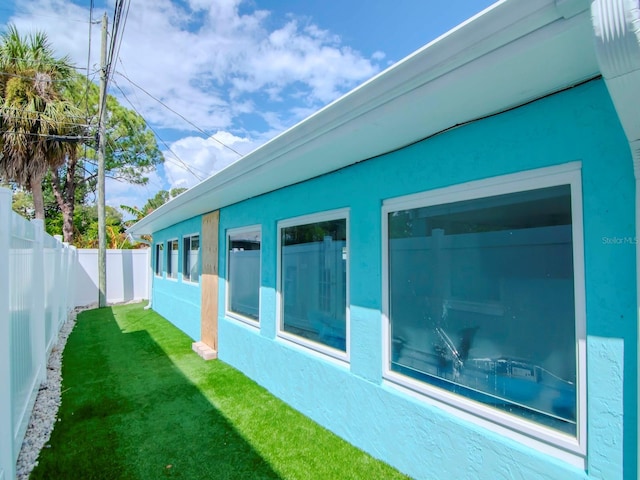view of side of property featuring a yard, a fenced backyard, and stucco siding