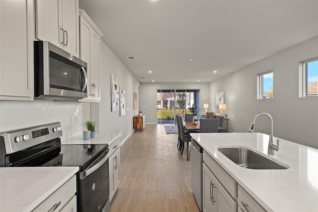 kitchen featuring stainless steel appliances, tasteful backsplash, plenty of natural light, and sink