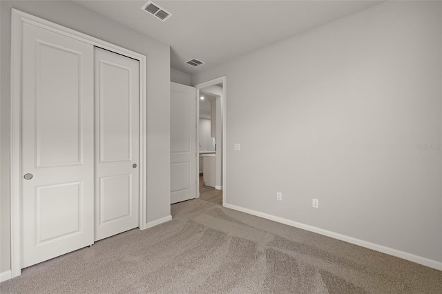 unfurnished bedroom featuring light carpet and a closet