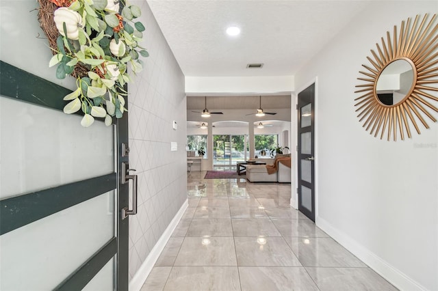 corridor featuring a textured ceiling and tile walls