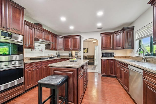 kitchen featuring sink, a kitchen breakfast bar, a center island, stainless steel appliances, and light wood-type flooring