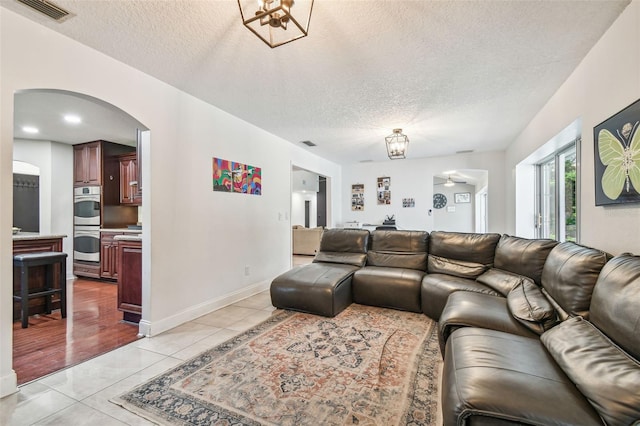 living room featuring light tile patterned floors, a notable chandelier, and a textured ceiling