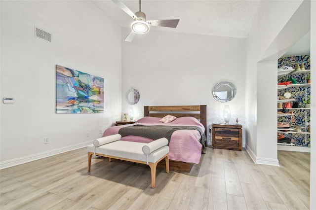 bedroom featuring ceiling fan, high vaulted ceiling, light hardwood / wood-style floors, and a textured ceiling