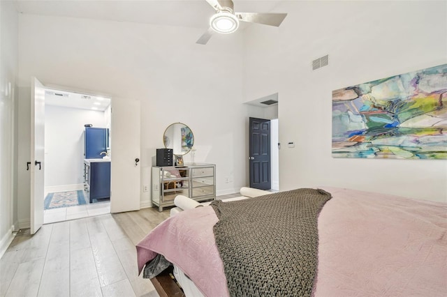 bedroom featuring a high ceiling, ceiling fan, and light hardwood / wood-style flooring