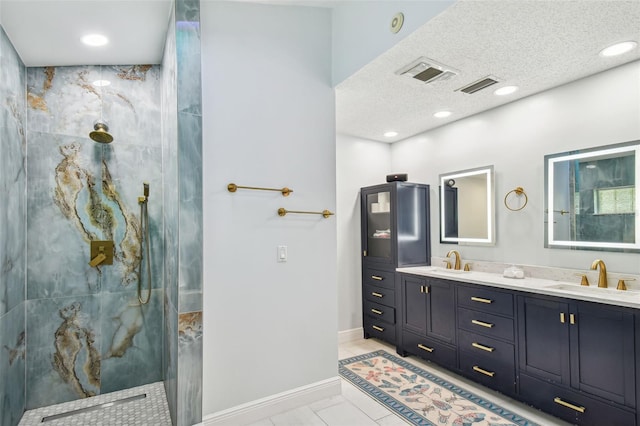 bathroom featuring tile patterned flooring, vanity, tiled shower, and a textured ceiling