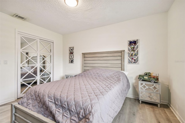 bedroom with a textured ceiling and light wood-type flooring