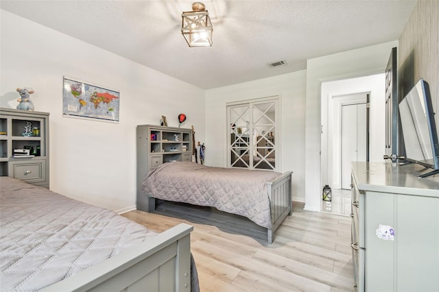 bedroom featuring light hardwood / wood-style flooring and a textured ceiling