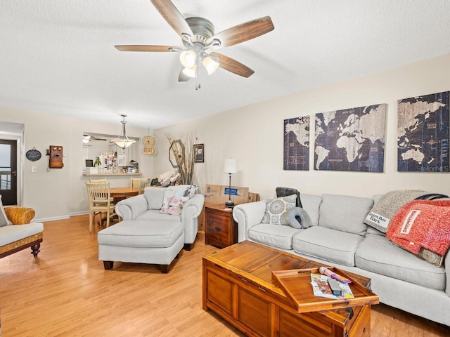 living room featuring a textured ceiling, ceiling fan, and light hardwood / wood-style flooring