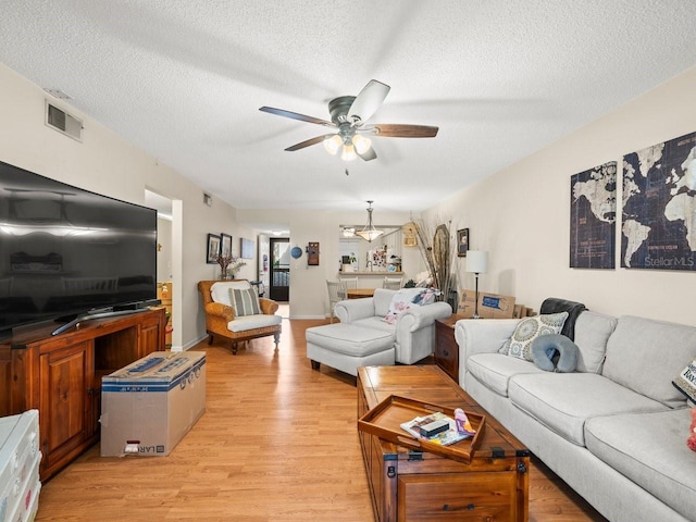 living room featuring ceiling fan, a textured ceiling, and light hardwood / wood-style flooring