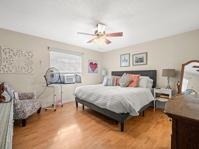 bedroom with ceiling fan, cooling unit, a textured ceiling, and light hardwood / wood-style floors