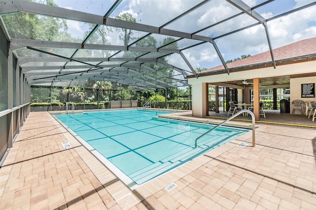 view of swimming pool with ceiling fan, a patio, and a lanai