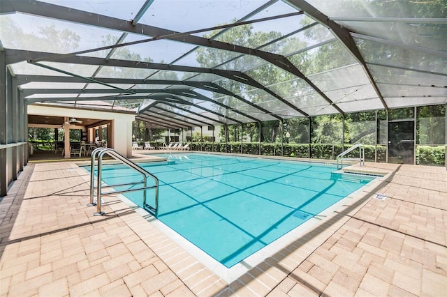 view of swimming pool featuring glass enclosure and a patio