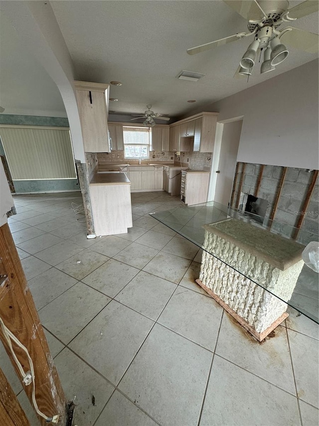 kitchen featuring light tile patterned flooring, backsplash, light brown cabinets, kitchen peninsula, and ceiling fan