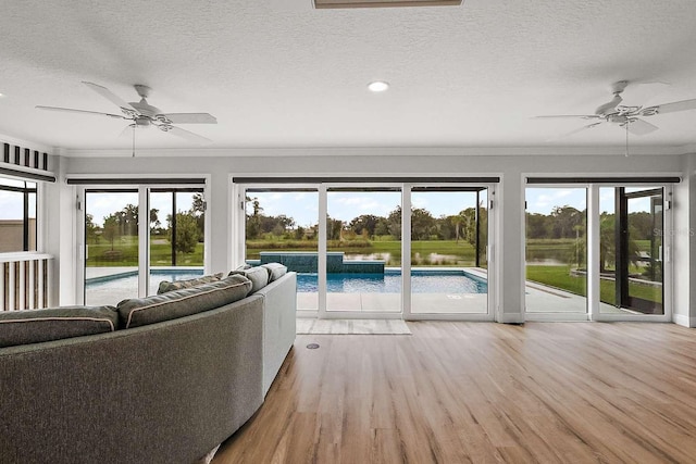 unfurnished living room featuring ornamental molding, light wood-type flooring, ceiling fan, and a water view