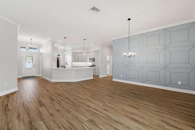 unfurnished living room with ornamental molding, hardwood / wood-style flooring, and a notable chandelier