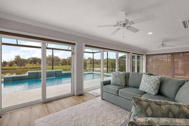 sunroom featuring ceiling fan and a water view