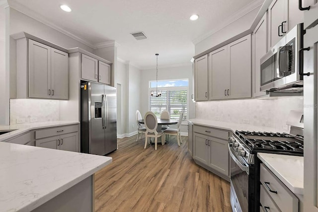 kitchen with appliances with stainless steel finishes, gray cabinetry, and light hardwood / wood-style flooring