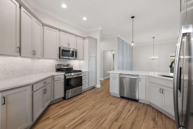 kitchen featuring kitchen peninsula, decorative light fixtures, stainless steel appliances, crown molding, and light hardwood / wood-style floors