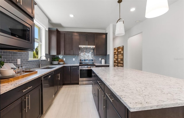 kitchen with appliances with stainless steel finishes, backsplash, a kitchen island, and sink