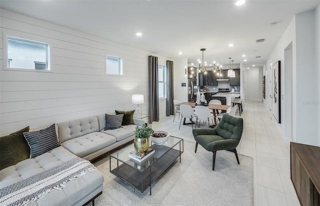 living room featuring wood walls, light tile patterned floors, and a chandelier