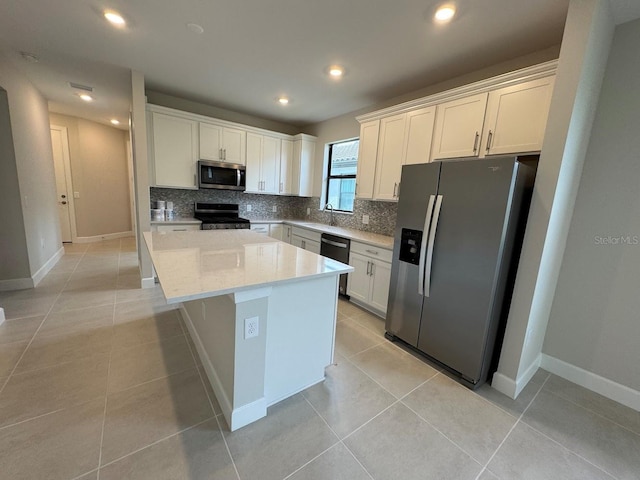 kitchen with a center island, white cabinets, decorative backsplash, light tile patterned floors, and appliances with stainless steel finishes