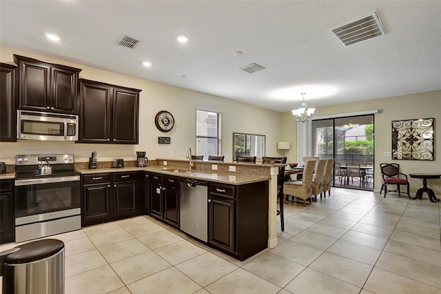 kitchen featuring kitchen peninsula, stainless steel appliances, sink, light tile patterned floors, and a notable chandelier