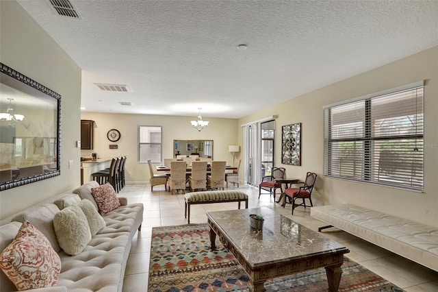 living room with light tile patterned flooring, a textured ceiling, and an inviting chandelier