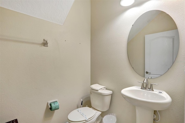 bathroom featuring a textured ceiling, toilet, lofted ceiling, and sink