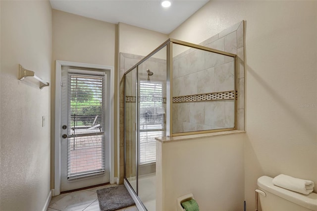 bathroom with tile patterned floors, toilet, and a shower with shower door