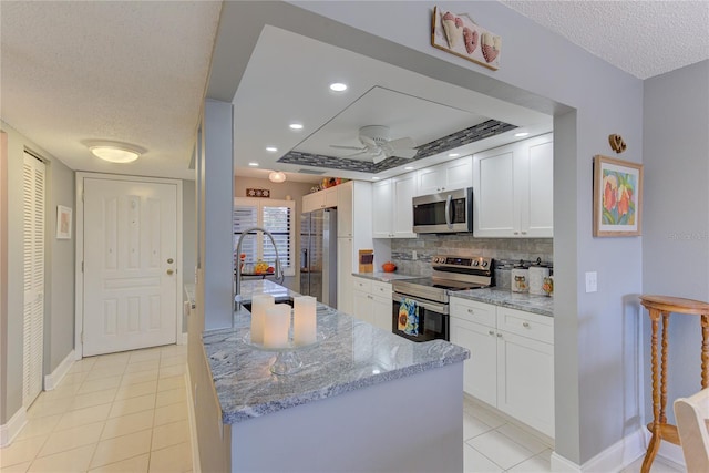 kitchen with light stone countertops, appliances with stainless steel finishes, a textured ceiling, white cabinetry, and light tile patterned floors