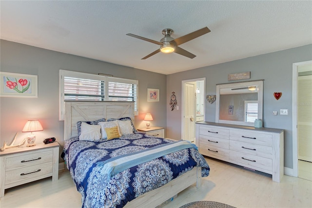 bedroom with light hardwood / wood-style flooring, a textured ceiling, and ceiling fan