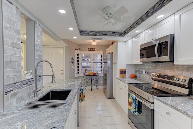 kitchen featuring light stone countertops, sink, backsplash, white cabinetry, and stainless steel appliances