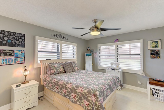 bedroom with a textured ceiling, multiple windows, and ceiling fan