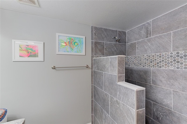 bathroom with a tile shower and a textured ceiling