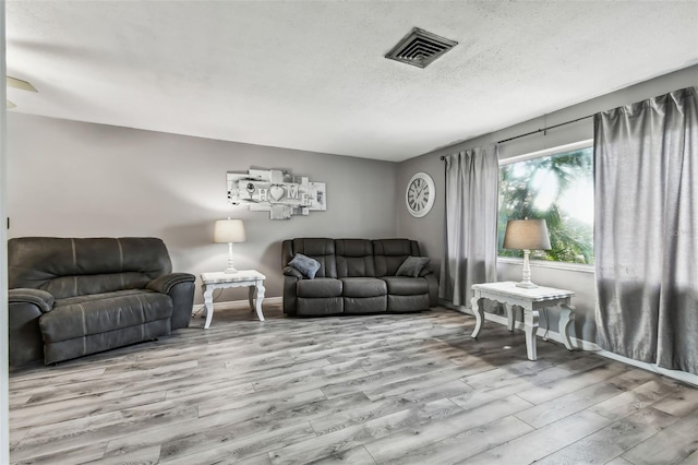 living room featuring light hardwood / wood-style flooring and a textured ceiling